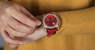 woman hand holding red watch on yellow background